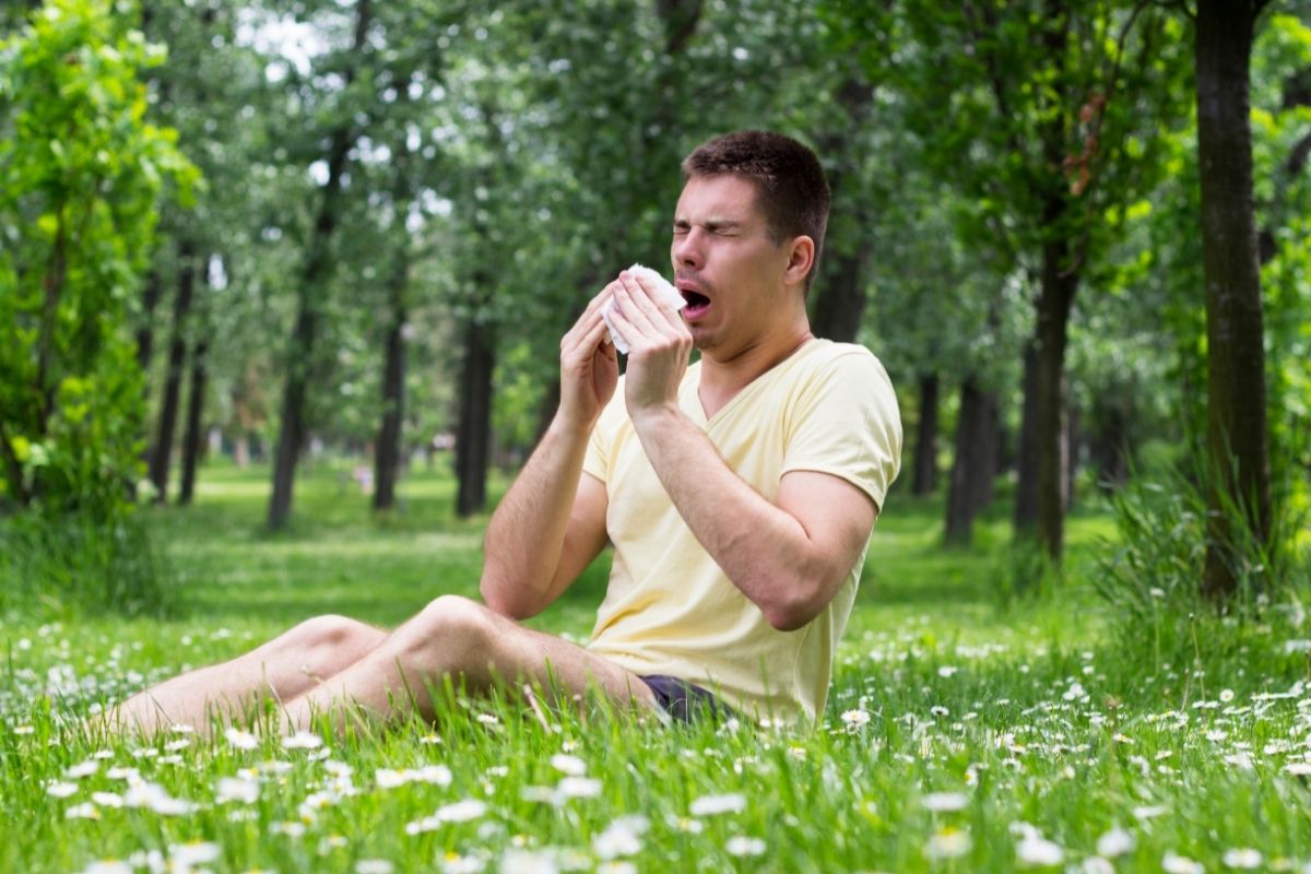 Man about to sneeze while sitting on grass